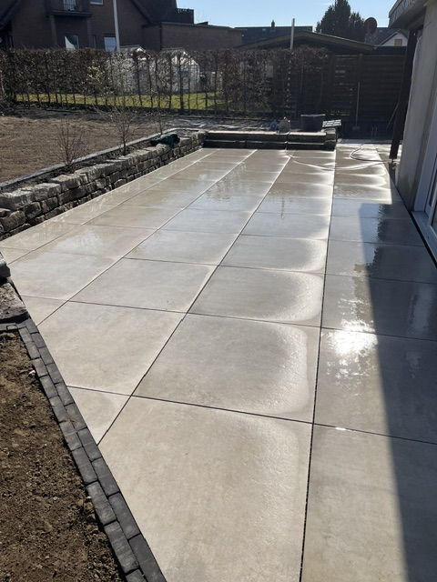 Large terrace in beige large format porcelain stoneware, framed by a natural stone wall