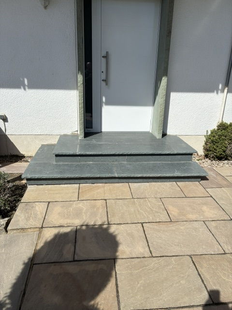 House entrance with dark natural stone block steps and sandstone paving slabs
