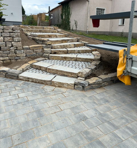 Natural stone steps in shell limestone with cobble inlay and adjoining dry stone wall