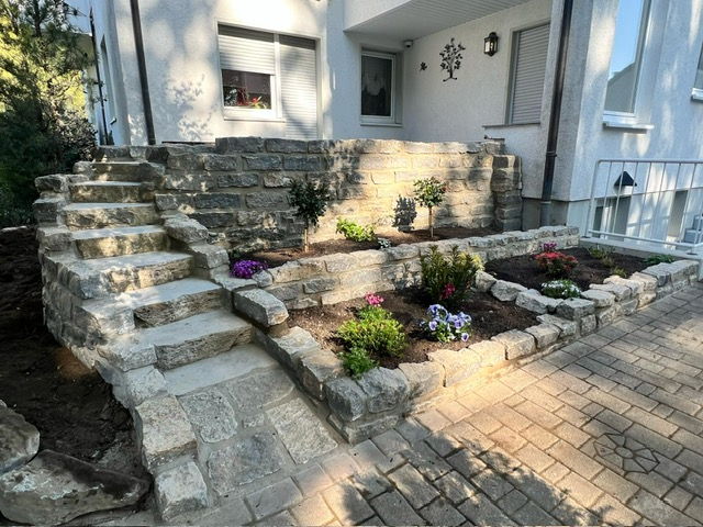 Natural stone steps and dry stone wall with a newly planted perennial bed at the house entrance