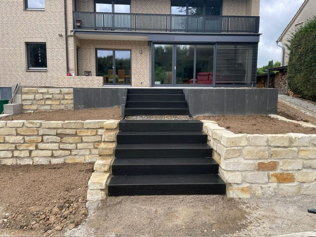 Wide flight of dark block steps between two sandstone dry stone walls