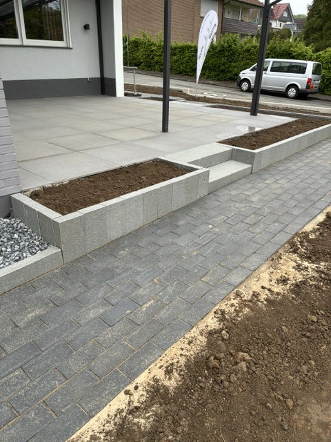Paving work in the front garden of a new build with anthracite pavers, concrete palisades and terrace slabs